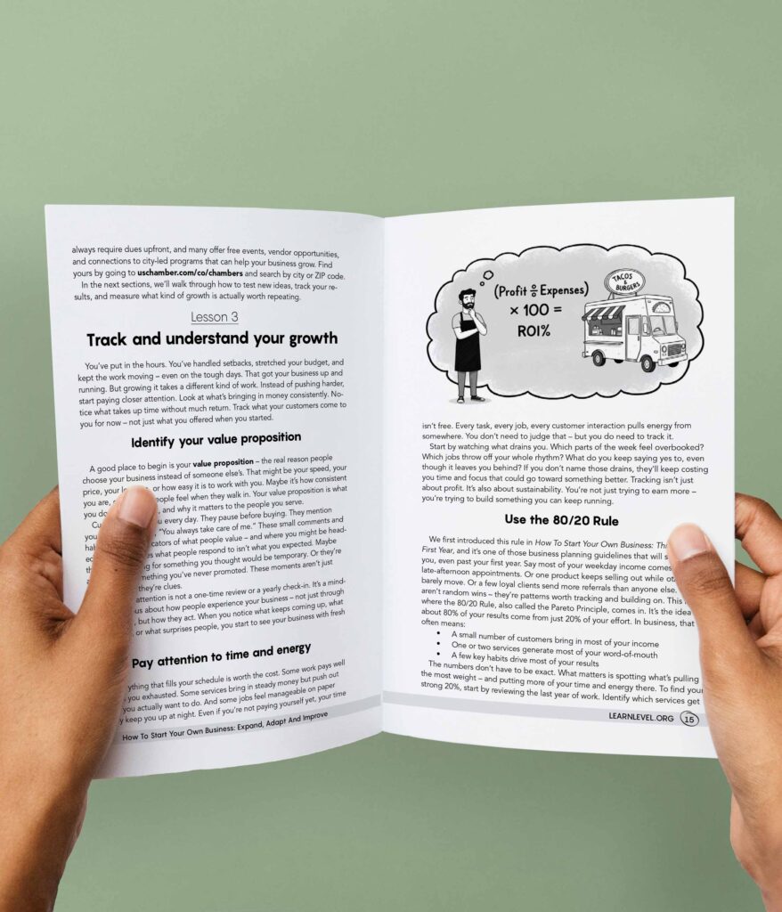 Hands holding an opened printed version of Level's prison education guide How To Start Your Own Business: Expand, Adapt And Improve